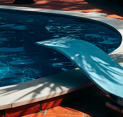 Diving board over a clean kidney-shaped pool on a tidy patio in Clarcona, FL