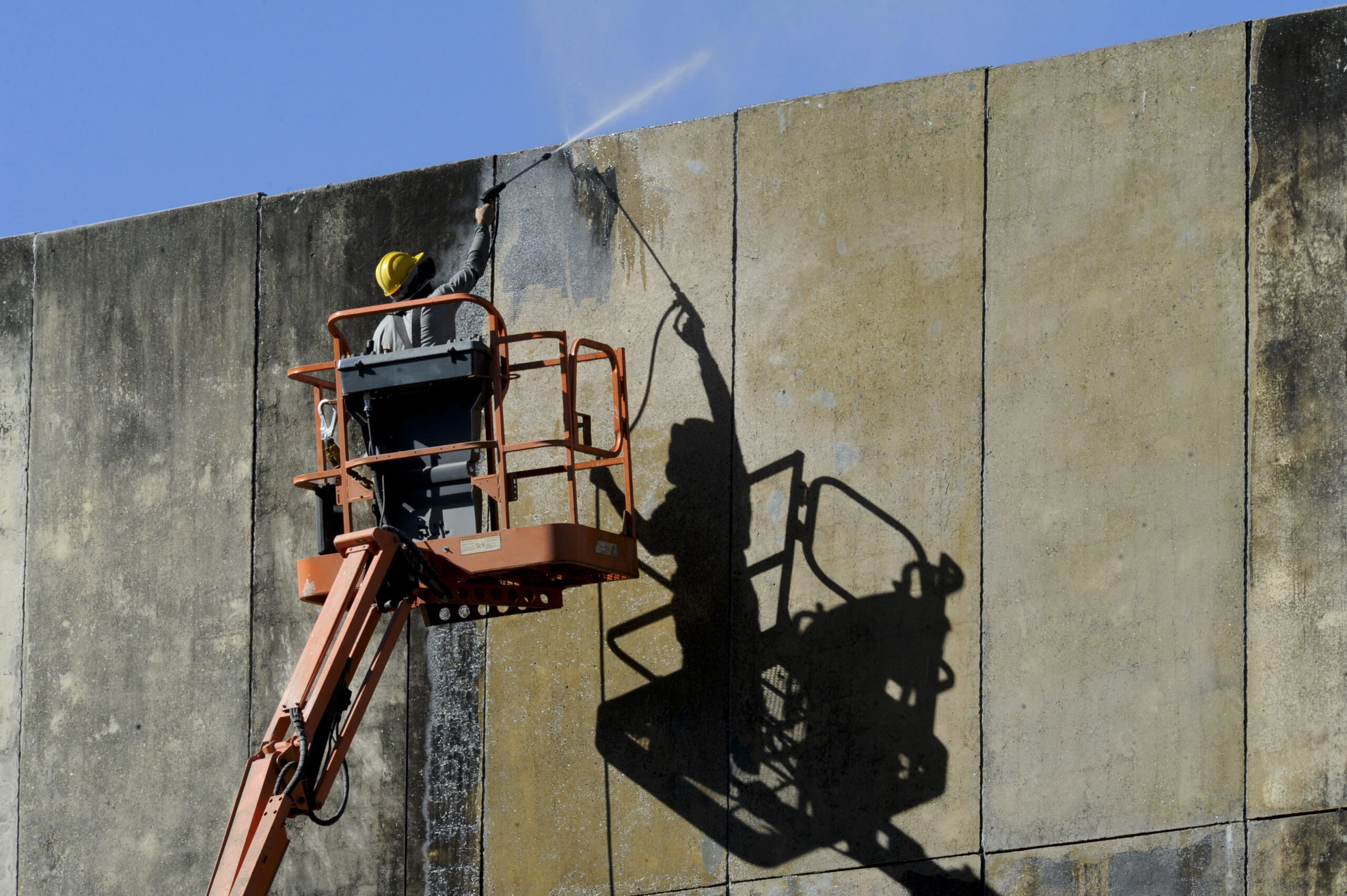 Worker cleaning a commercial building exterior from a lift