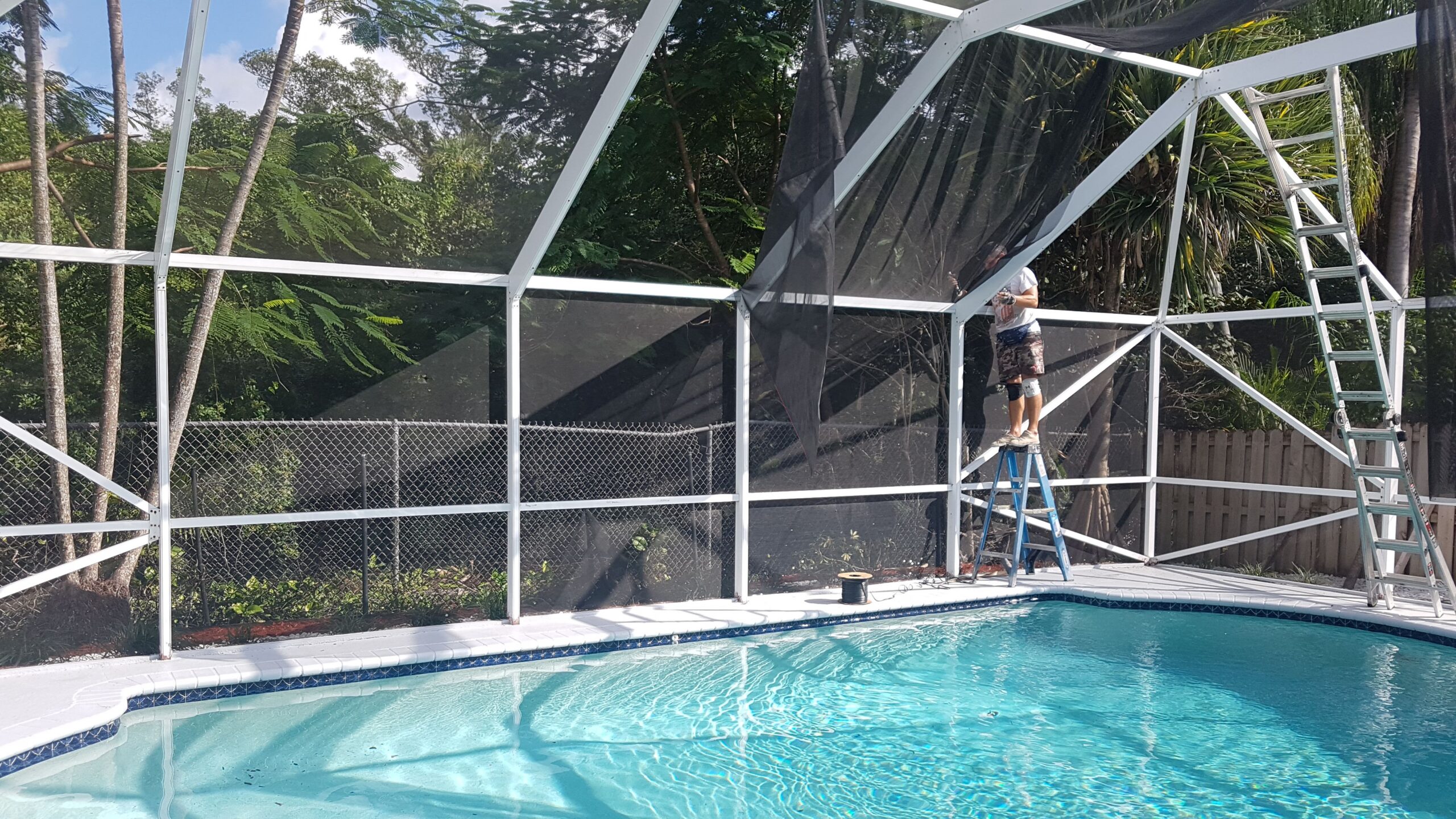 White aluminum pool screen enclosure over a backyard pool