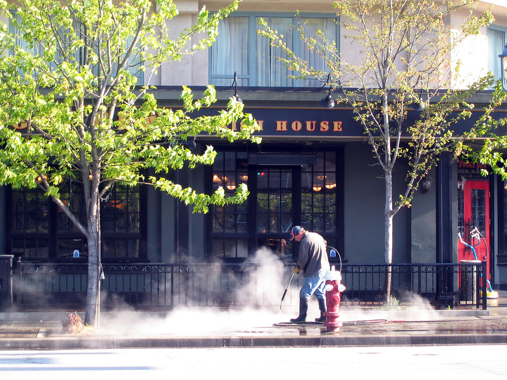 Worker cleaning a city sidewalk with a pressure washer