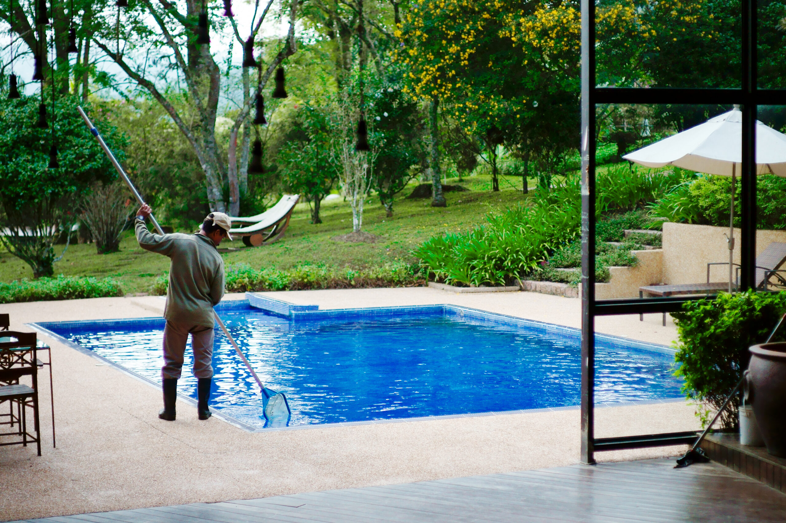 Pool technician working on a deck, seen from behind